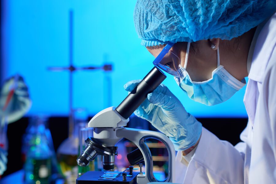 Laboratorio médico - Científica observando a través de un microscopio en un laboratorio