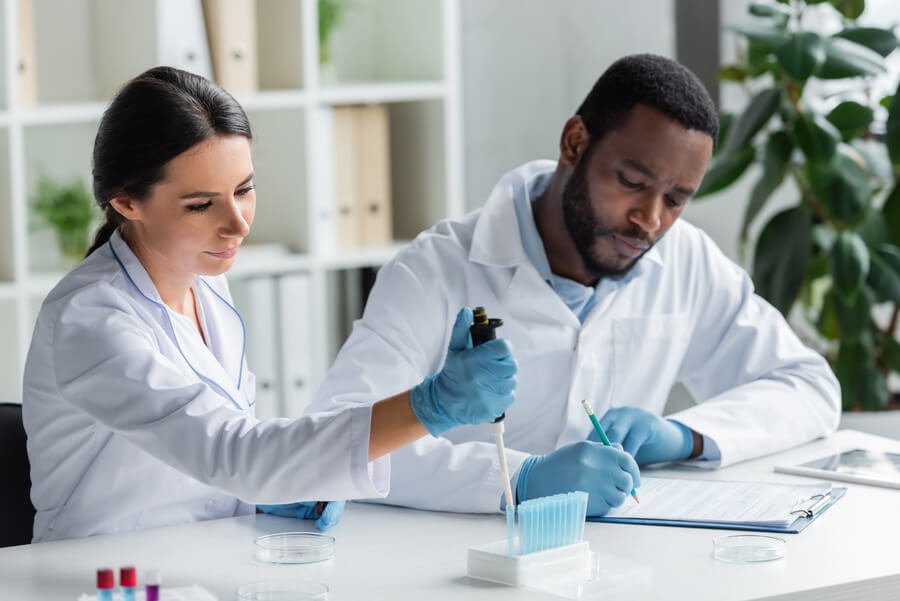Dos científicos en laboratorio analizando una muestra líquida con atención.