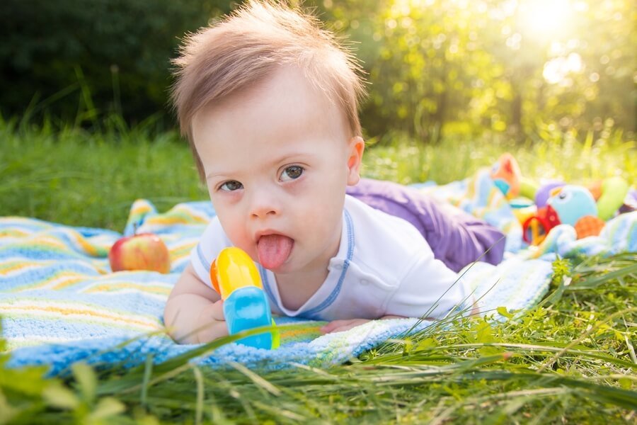 Importancia de la citogenética oncología - Niño pequeño acostado sobre una manta en el césped, jugando con un juguete de colores.
