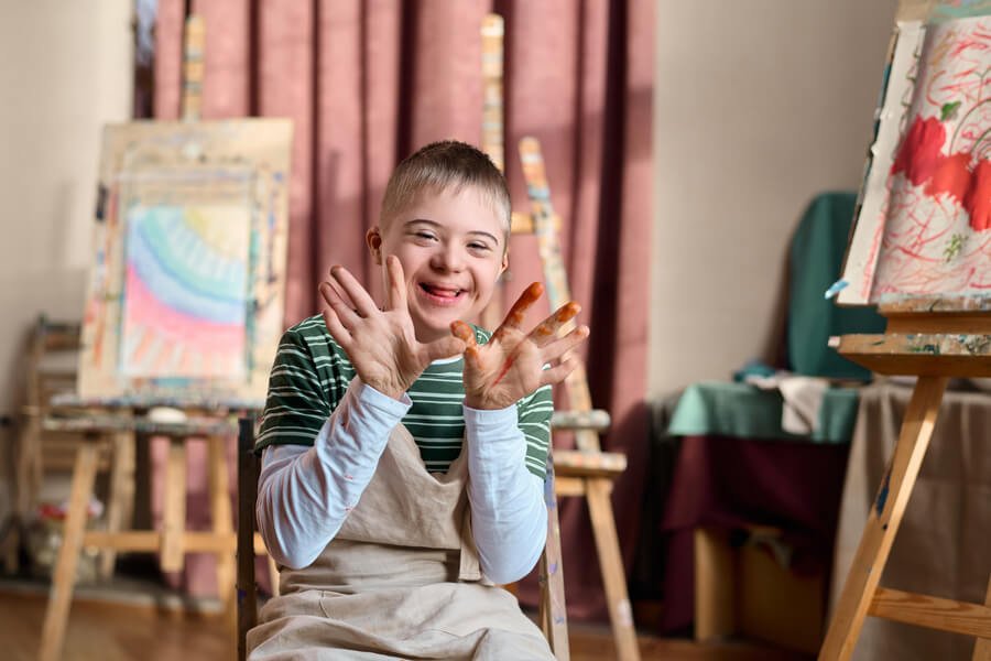 Importancia de la citogenética - Niño sonriente con las manos manchadas de pintura durante una actividad artística.
